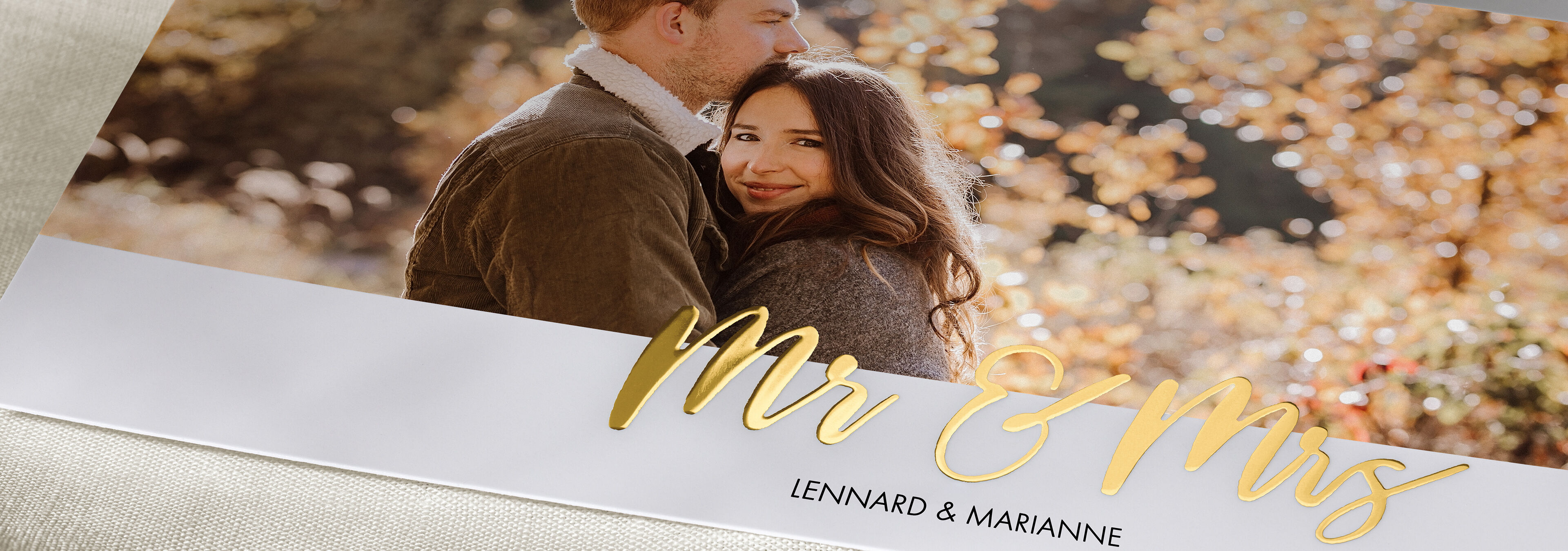 Sretan par sjedi u prirodi, okružen jesenskim bojama, s natpisom 'Mr & Mrs'.